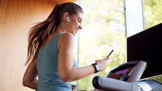 Best running headphones: Woman wearing headphones on treadmill