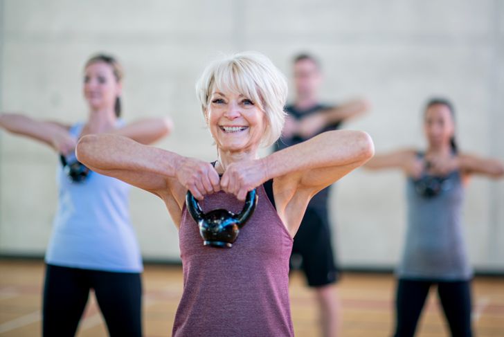 Senior woman in fitness class using a kettlebell