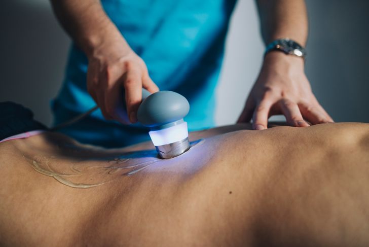 Physiotherapist using ultrasound to treat patient's back