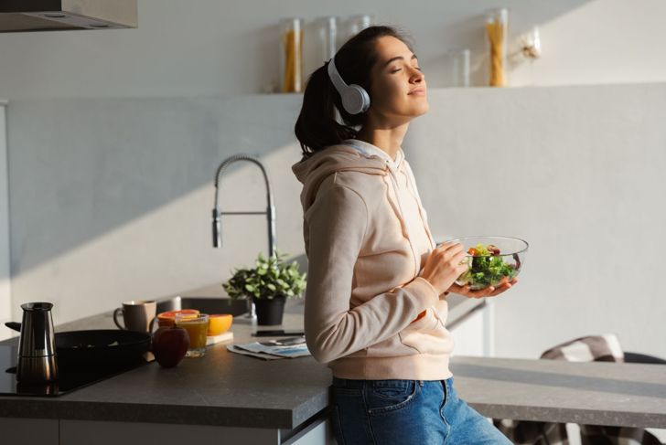 smiling woman listening to music with salad
