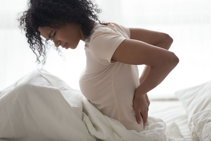 woman with sore back in bed