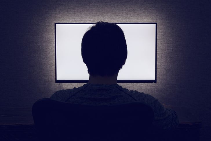 Man looks in front of empty monitor in dark room