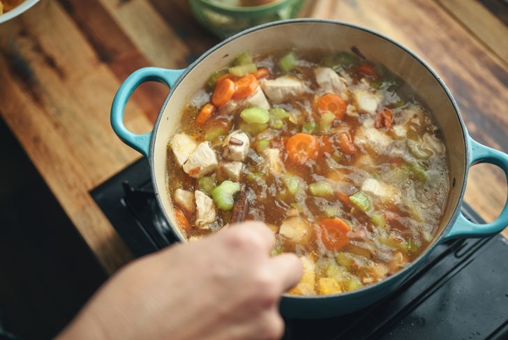 Cooking chicken noodle soup with vegetables in pot