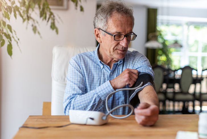An elderly man checking his own blood pressure