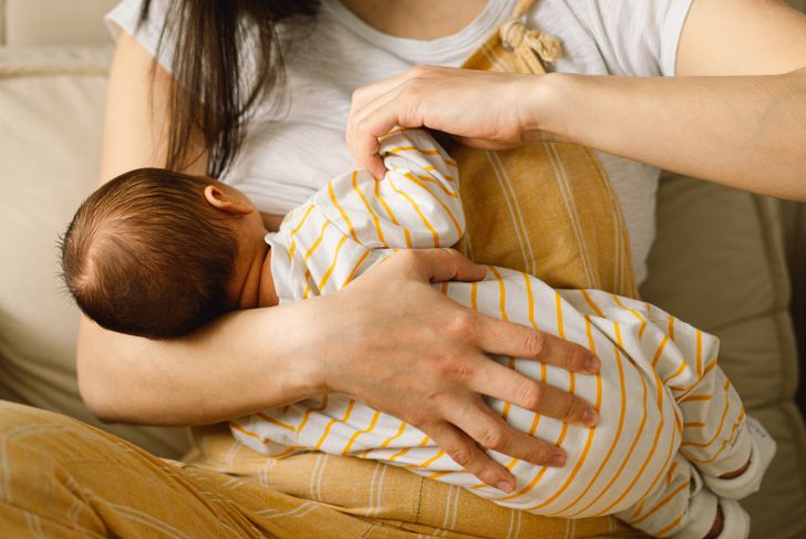 Newborn baby boy sucks milk from mother's breast