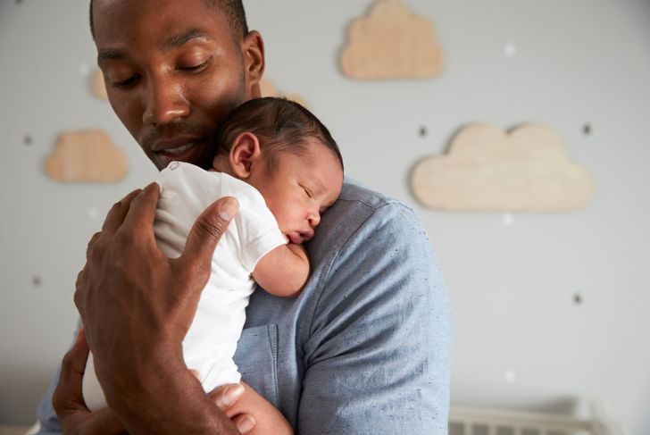 Father holds newborn son in nursery
