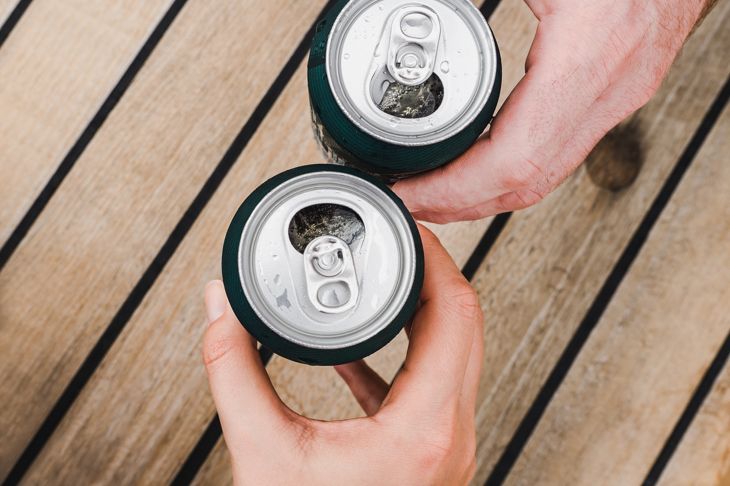 Two cans of beer, female and male hands