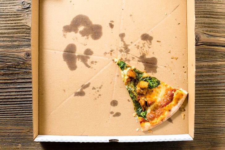 A slice of pizza in a cardboard pizza box