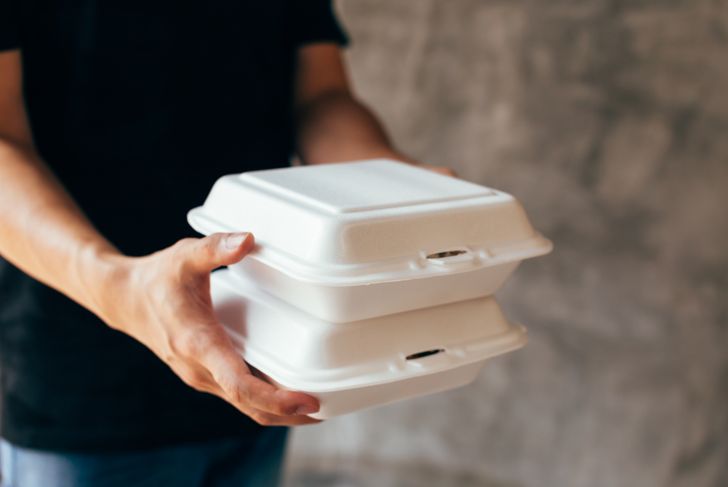Close-up of delivery man handing over a piece of foam lunch box
