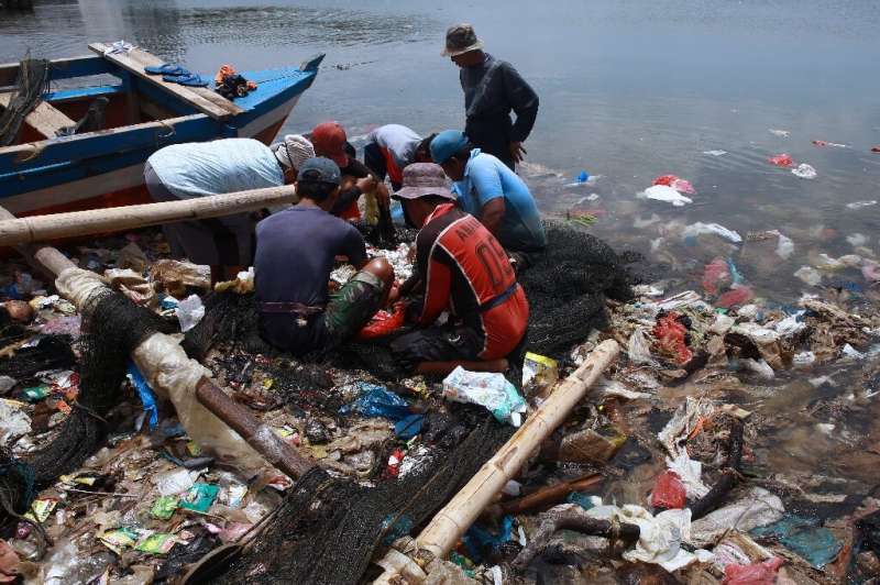Fishermen sort their catch from a net in plastic-polluted waters in Bandar Lampung, Indonesia