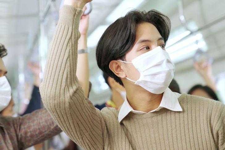 Young man wearing face mask travels in crowded subway