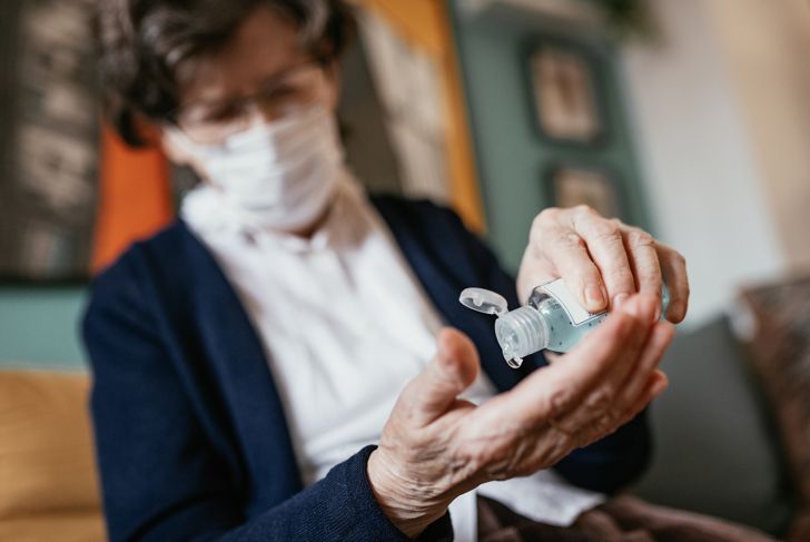 Senior woman applying hand sanitizer at home