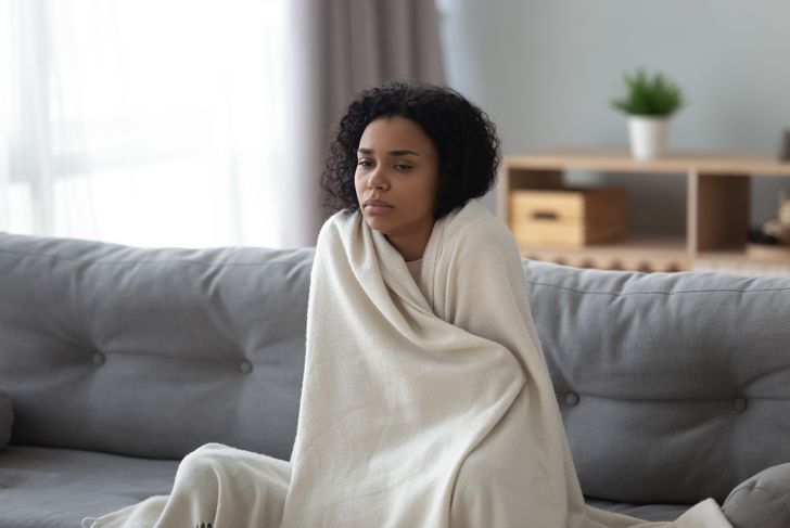 sick woman feels cold covered with blanket at home