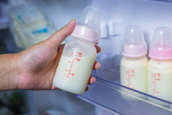 Close-up of hand holding bottle of breast milk in stock