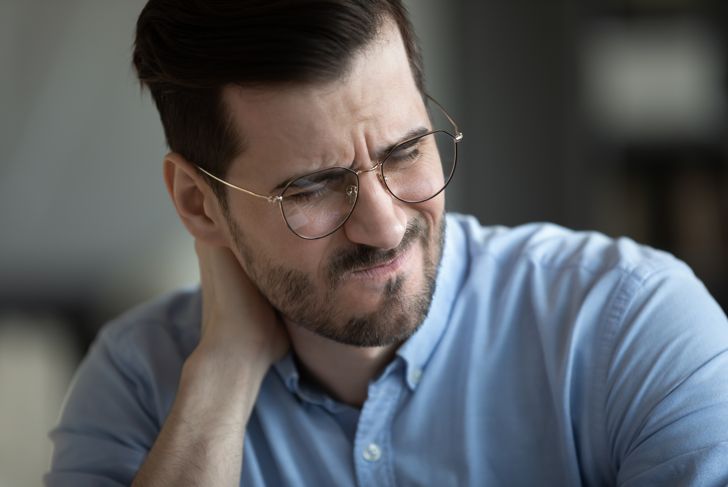Close up view frowning face of businessman feeling pain in neck?