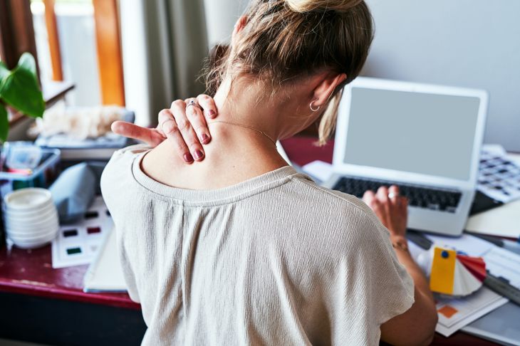 woman holds neck in pain