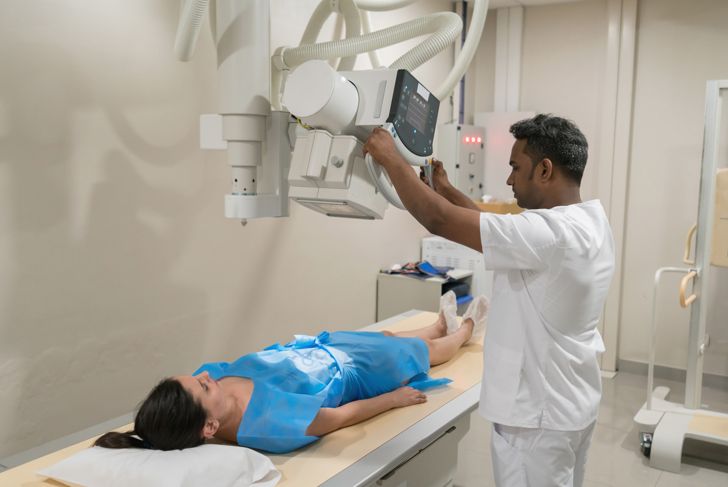 Female patient is ready for an x-ray and radiologist prepares the machine