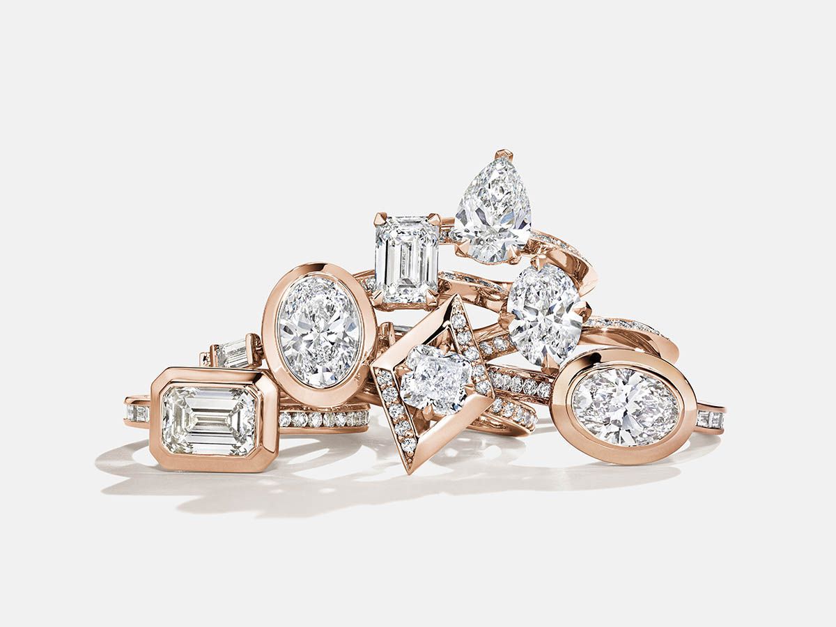 A stack of diamonds and rose gold rings against a white background.