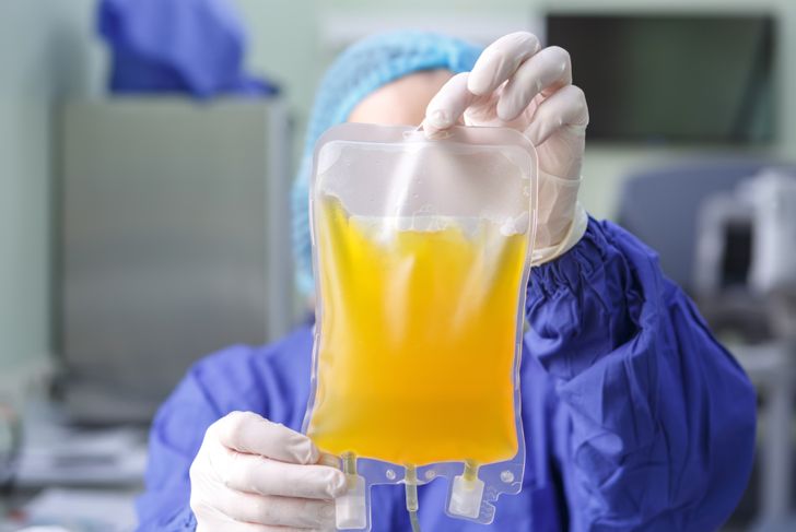 Gloved hands of a medical worker holding a bag of blood plasma close-up