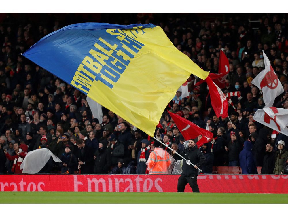 A giant flag in the national colours of Ukraine is waved ahead of the English Premier League football match between Arsenal and Liverpool in London. Never has the free world been so united, yet so helpless.