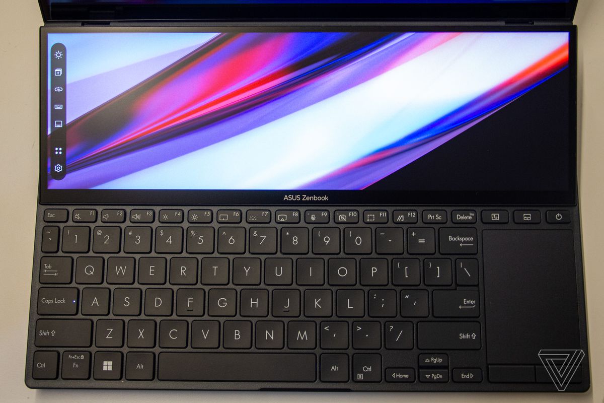 The keyboard deck of the Asus Zenbook Pro Duo 14 seen from above.  The ScreenPad shows a multicolored background with a taskbar on the left.