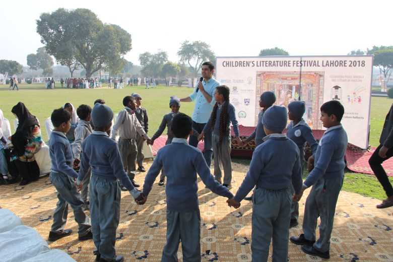 A group of young people stand in a circle holding hands.