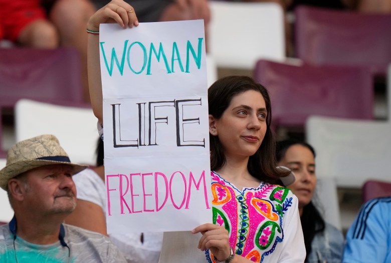 A woman holds up a sign that reads woman life freedom.